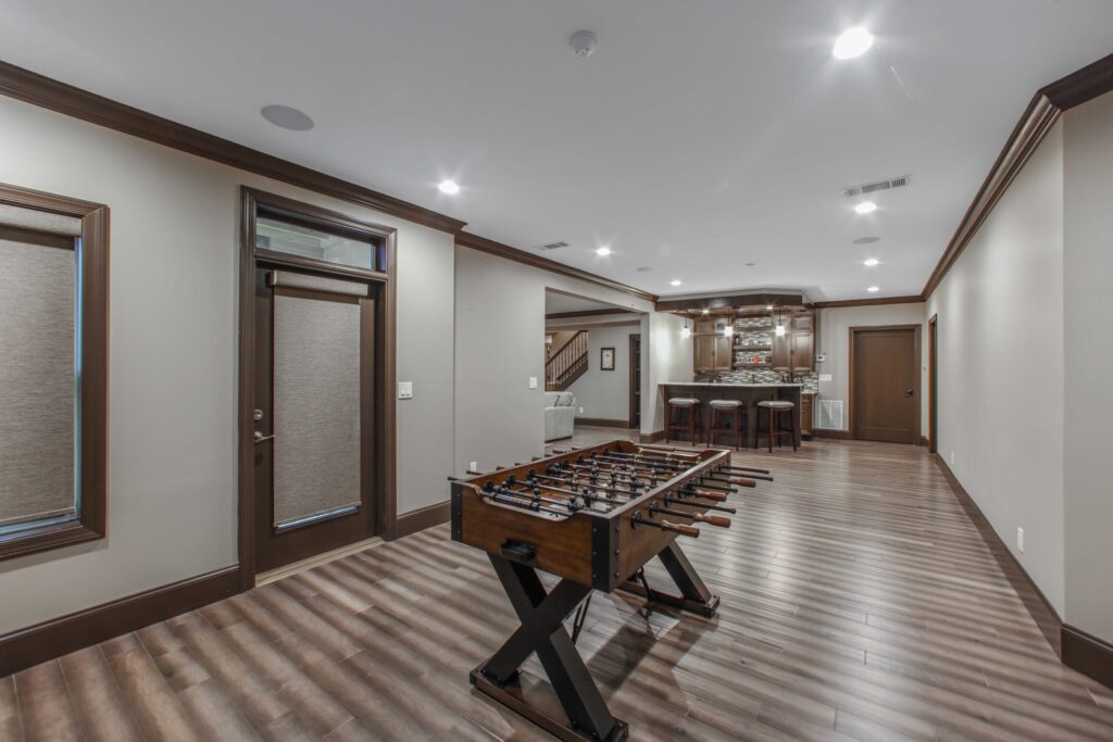 Finished basement with foosball table, modern lighting, and bar area, showcasing functional living space for entertainment and relaxation in Cumming, GA.