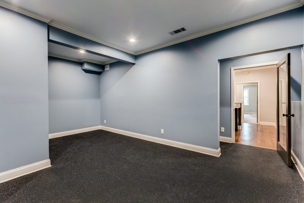 Basement room with blue walls and dark flooring, showcasing potential for custom home additions and remodeling in Alpharetta.