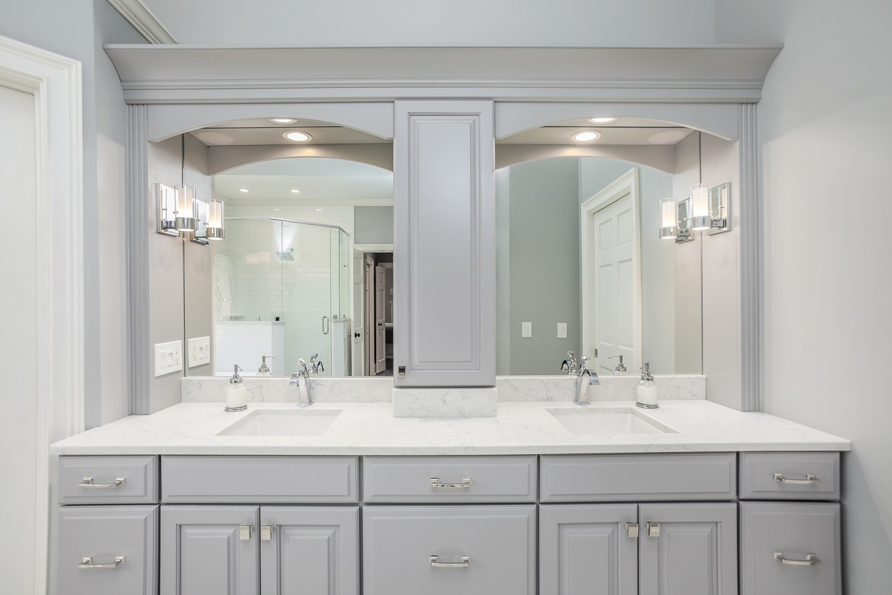 Modern bathroom vanity with dual sinks, gray cabinetry, marble countertop, and stylish lighting, showcasing a clean and functional design for a remodeling project.