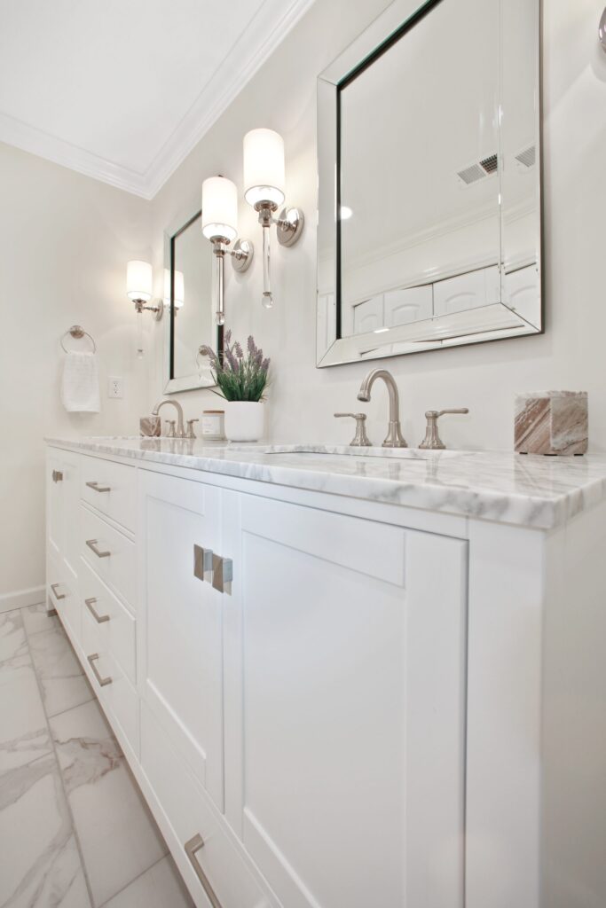 Modern bathroom vanity with dual mirrors, stylish wall sconces, and a marble countertop, featuring a potted plant and elegant fixtures, showcasing high-end design for remodeling services in Alpharetta, GA.