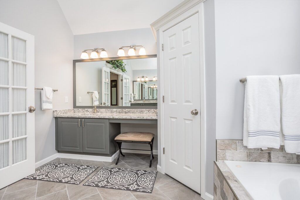 Modern bathroom interior featuring a double vanity with granite countertop, elegant lighting, and decorative rugs, showcasing a stylish renovation ideal for home remodeling in Alpharetta, GA.