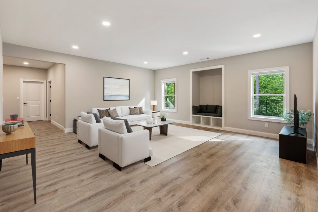 Modern living room design featuring a light color palette, white sofas, a coffee table, and a cozy nook with large windows, highlighting the Cheval Rue Court basement renovation by HomeVantage in Suwanee, GA.