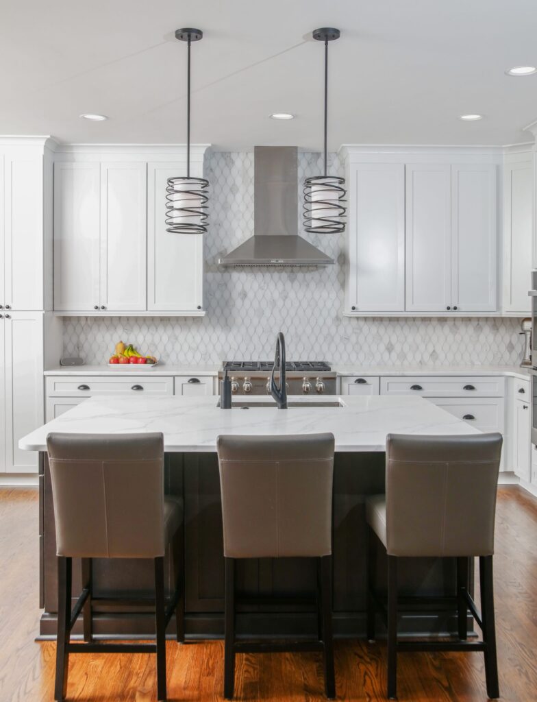 Modern kitchen remodel featuring white cabinets, marble countertop, stainless steel appliances, and stylish pendant lighting in a contemporary design.