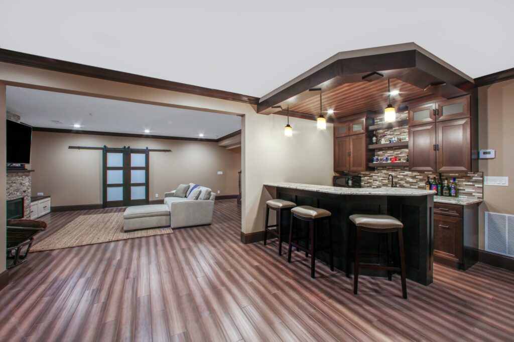 Modern finished basement with a bar area, comfortable seating, and warm wood accents, showcasing a functional entertainment space ideal for gatherings and relaxation.