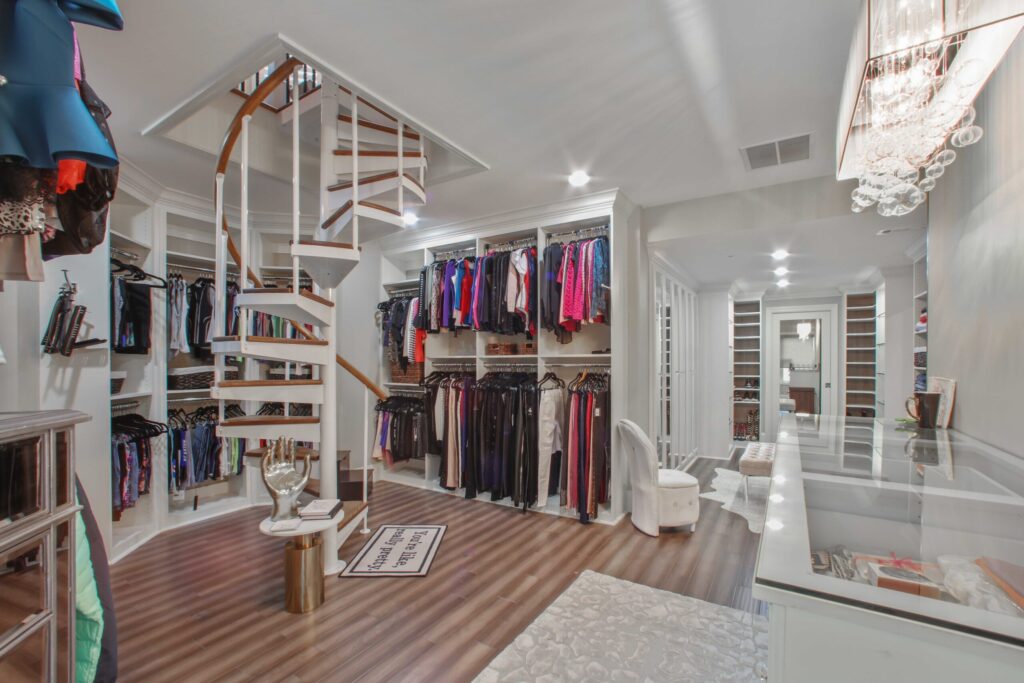 Spacious walk-in closet featuring a spiral staircase, organized clothing racks, elegant lighting, and modern design elements in a renovated basement in Roswell, GA.