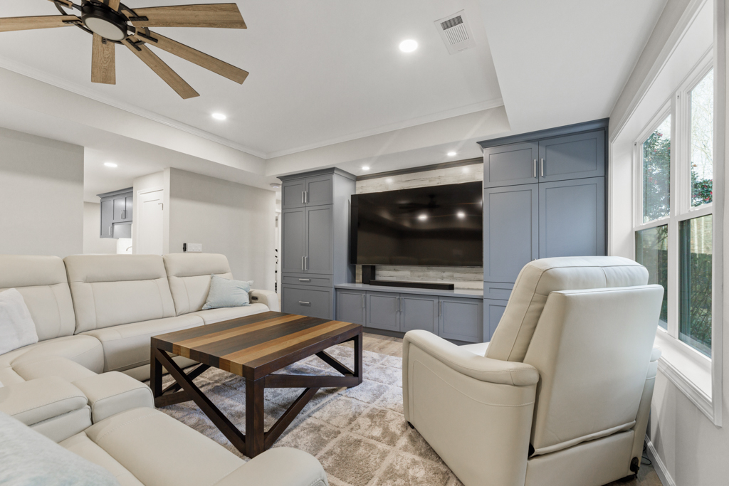 Modern living room featuring a light-colored sectional sofa, a wooden coffee table, and a large flat-screen TV mounted on a gray cabinet, emphasizing a cohesive design for home remodeling.