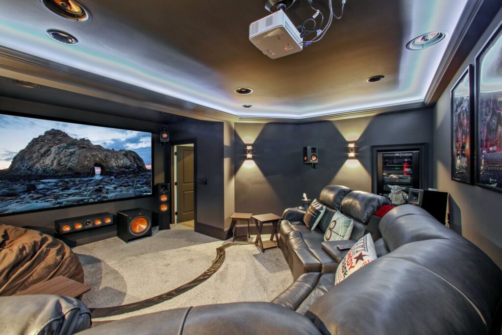 Modern basement home theater with leather seating, large screen displaying scenic view, surround sound speakers, and ambient lighting, showcasing HomeVantage's remodeling expertise in Marietta, GA.