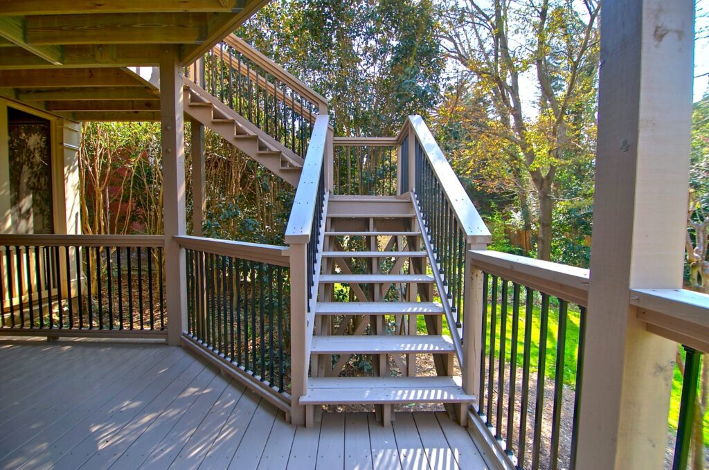 Outdoor wooden staircase leading to a deck, surrounded by greenery, showcasing functional design for enhanced outdoor living spaces in Marietta, GA.