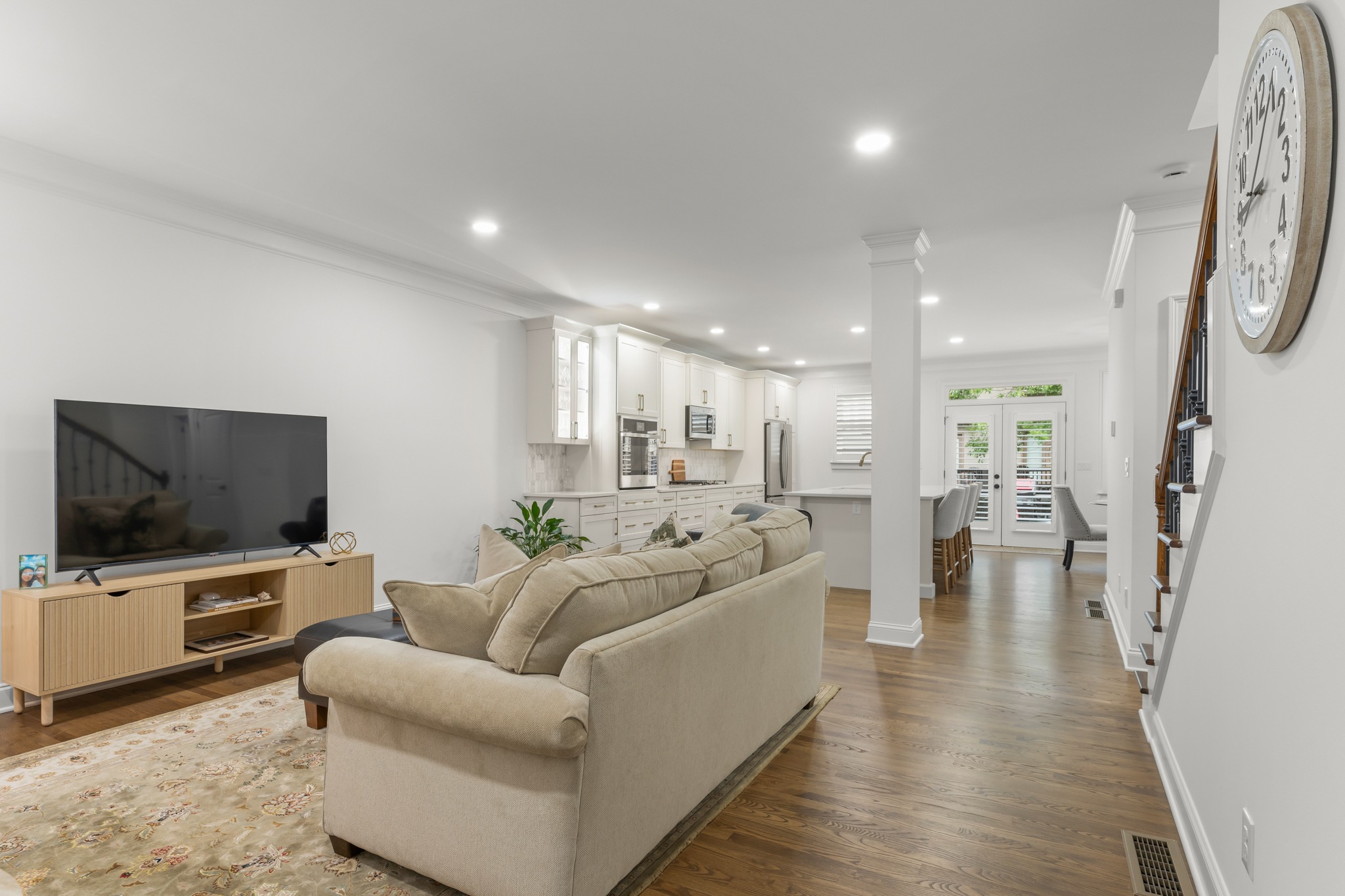Modern kitchen renovation featuring an open layout with a beige sofa in the foreground, a large TV on a wooden stand, and bright cabinetry in the background, showcasing HomeVantage's commitment to quality craftsmanship in residential remodeling.