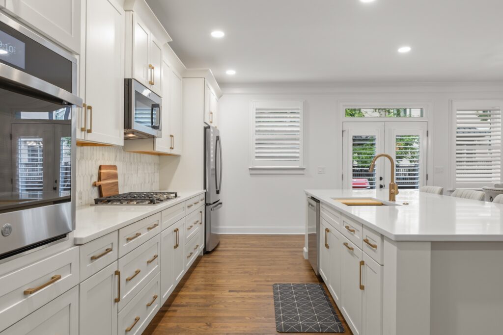 Modern kitchen renovation featuring white cabinetry, stainless steel appliances, and a spacious island with a sink, located in Ridge Towne, Duluth, GA.