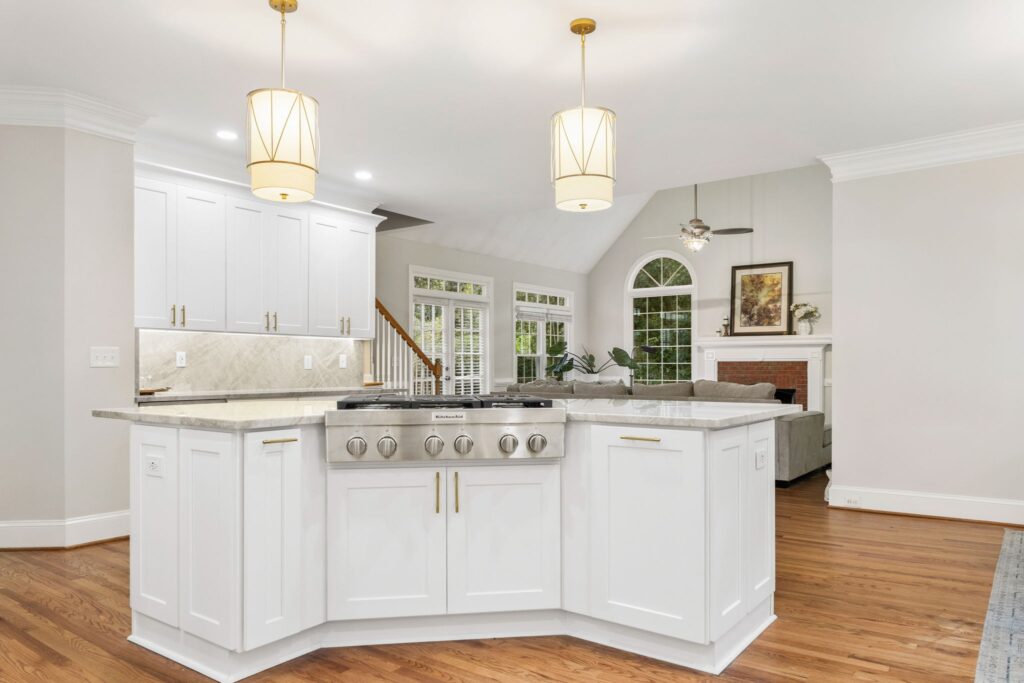 Modern kitchen remodel featuring white cabinetry, granite countertops, and pendant lighting, showcasing open design with living area in background, emphasizing HomeVantage's craftsmanship.