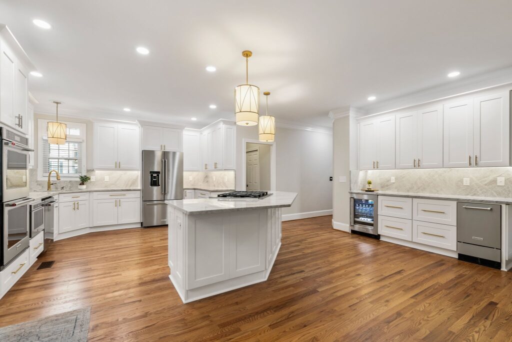 Modern kitchen design featuring white cabinetry, marble countertops, stainless steel appliances, and hardwood flooring, showcasing a completed remodeling project by HomeVantage in Shadow Creek Chase, Alpharetta, GA.