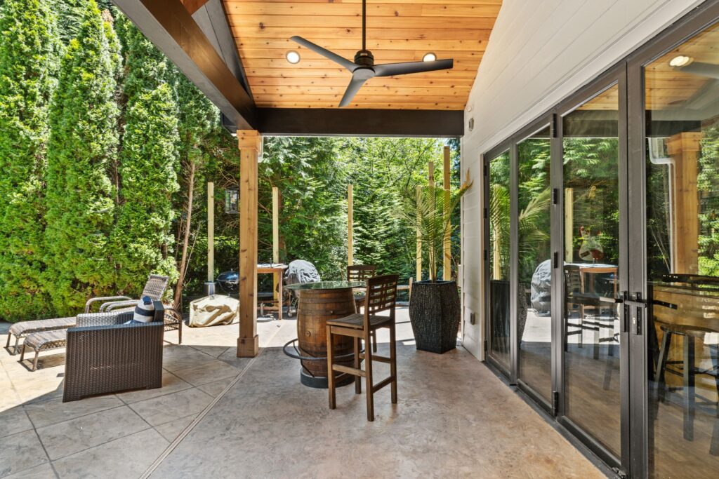 Outdoor living space with modern patio furniture, wooden ceiling, and lush greenery, showcasing a cohesive design ideal for whole home remodeling in Cumming, GA.