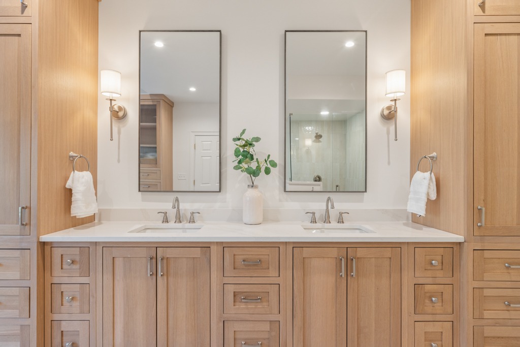 Modern bathroom design featuring dual sinks, wooden cabinetry, large mirrors, and stylish lighting, showcasing a renovation project by HomeVantage.
