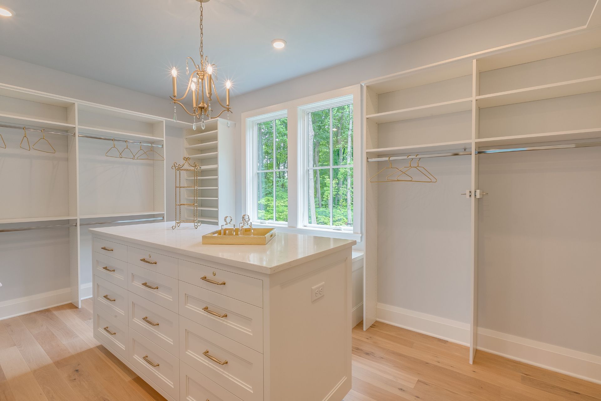 Walk-in closet featuring a central island with drawers, white shelving, and large windows providing natural light, illustrating organized home renovation design by HomeVantage.