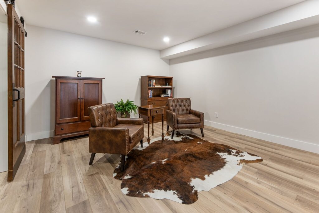 Modern basement interior featuring leather chairs, wooden furniture, and a cowhide rug in Roswell, GA.