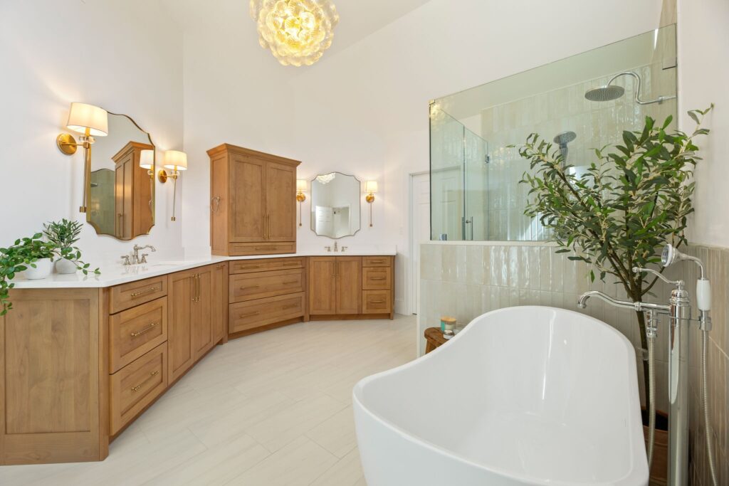 Bathroom design featuring wooden cabinets, modern fixtures, large mirrors, and a freestanding tub in a bright, spacious layout at Windermere Crossing, Cumming, GA.