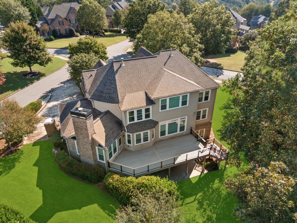 Aerial view of a modern two-story home with a spacious deck, surrounded by lush green landscaping in Cumming, GA, showcasing HomeVantage's outdoor remodeling project on Goodrick Lane.