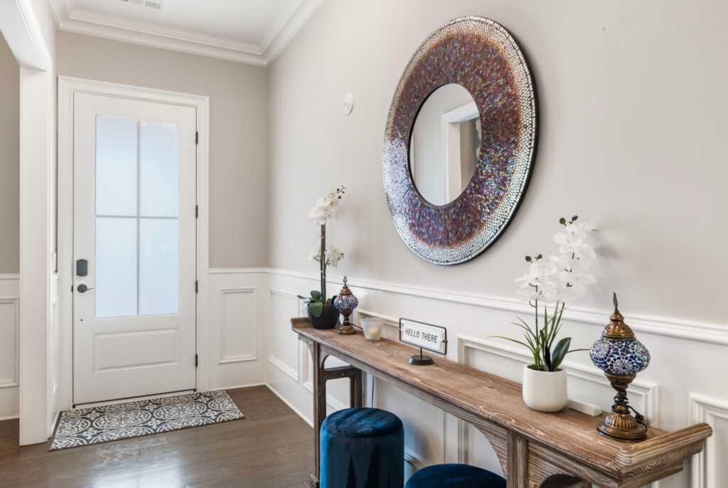 Elegant entryway featuring a decorative mirror, console table with vases and plants, and a stylish door, showcasing home remodeling design elements in Marietta, GA.