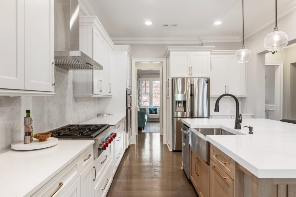Modern kitchen with white cabinetry, stainless steel appliances, and a large island featuring a quartz countertop, showcasing a blend of functionality and style for kitchen remodeling in Alpharetta, GA.